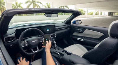 Person connecting a smartphone to a dashboard touchscreen inside a Miami car rental