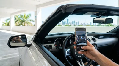 Person using a smartphone to photograph a dashboard and fuel gauge inside a car rental in Miami