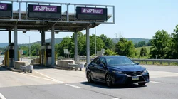 Driver in a white car rental passing through an E-ZPass toll plaza in Pennsylvania