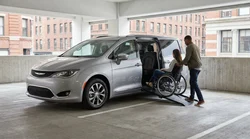 Person in a wheelchair using a ramp to board a car hire vehicle on a New York street