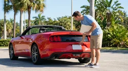 Person inspecting the rear license plate and registration tag on a car rental in Florida