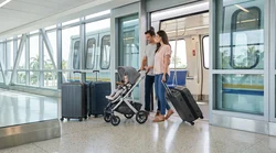 Traveler pushing a pram and luggage along a step-free walkway at the Miami airport car rental center