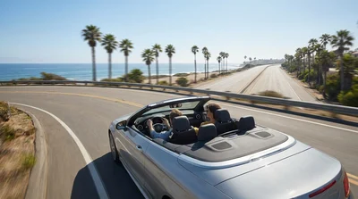 White SUV car rental driving along a scenic coastal road in California overlooking the ocean