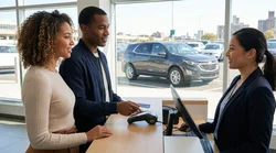 Hand tapping a contactless credit card on a payment terminal at a car rental desk in New York