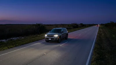 Headlights from a Miami car rental illuminate the empty I-75 highway as it cuts through the Everglades at dusk
