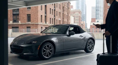 A shiny premium car rental parked on a busy street with the New York skyline behind it