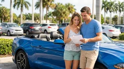 A white car rental driving on a sunny coastal highway lined with palm trees in Florida