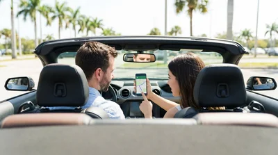 Driver using a smartphone navigation map mounted on the dashboard of a car rental on a sunny Orlando highway