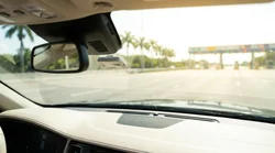 White car rental driving through an automated toll plaza on a sunny highway in Florida