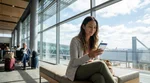 Traveler looking at a smartphone near a car hire counter inside a San Francisco airport terminal