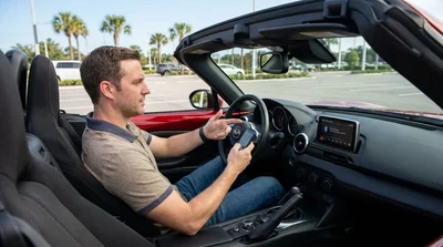 Driver tapping a smartphone screen near the dashboard display inside an Orlando car rental