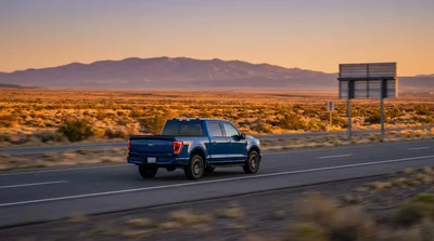 A white car rental driving past a Texas state border sign on a sunny desert highway