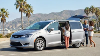 Two smiling passengers riding in a car rental along a scenic coastal highway in California