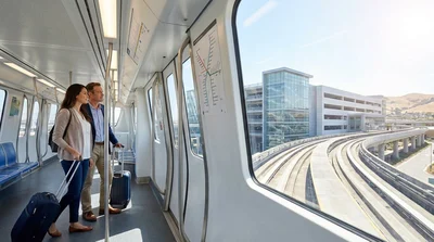 Red AirTrain traveling on elevated tracks toward the SFO car rental center in San Francisco