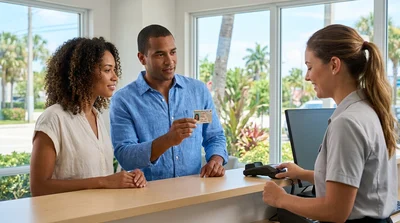 Person handing a damaged driving license to a car rental agent across a counter in Florida