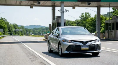 Driver in a car rental passing an electronic toll gantry on a Pennsylvania highway