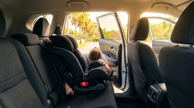 Black child safety seat installed in the back of a car rental in sunny Florida