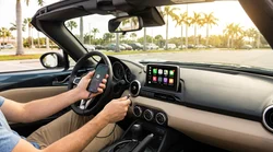 Driver setting up Apple CarPlay on a dashboard touchscreen inside a Florida car rental