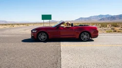 White car rental driving on a scenic highway in California with mountains in the background