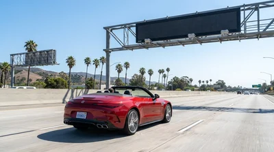 White car rental driving on a sunny California highway approaching a toll booth