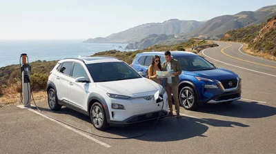 Modern electric car rental driving along a scenic sunlit coastal highway in California