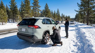 White car rental with snow chains driving on a snowy mountain road in California