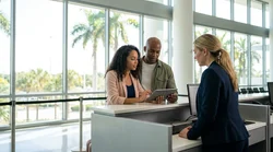 A traveler reviewing paperwork at a car rental counter inside a Florida airport terminal