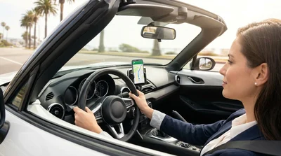 Dashboard mounted smartphone used for navigation inside a car rental on a sunny California highway