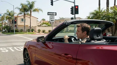 Driver in a car rental making a right turn at a red traffic light at a sunny California intersection