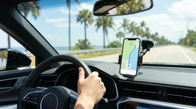 Driver looking at a smartphone map mounted on the dashboard of a car hire in Florida