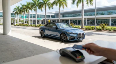 Customer handing a credit card to an agent at a car hire desk in Florida with keys on the counter