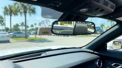 SunPass toll transponder mounted below the rearview mirror on the windshield of a Florida car rental