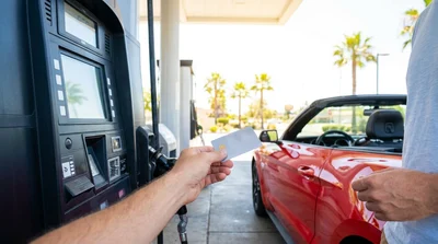 Person using a credit card at a gas station pump to refuel a car rental in California