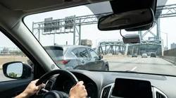 A silver car rental driving across a toll bridge towards the New York skyline