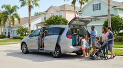 Family of seven loading luggage into a white SUV car rental parked on a sunny Orlando street