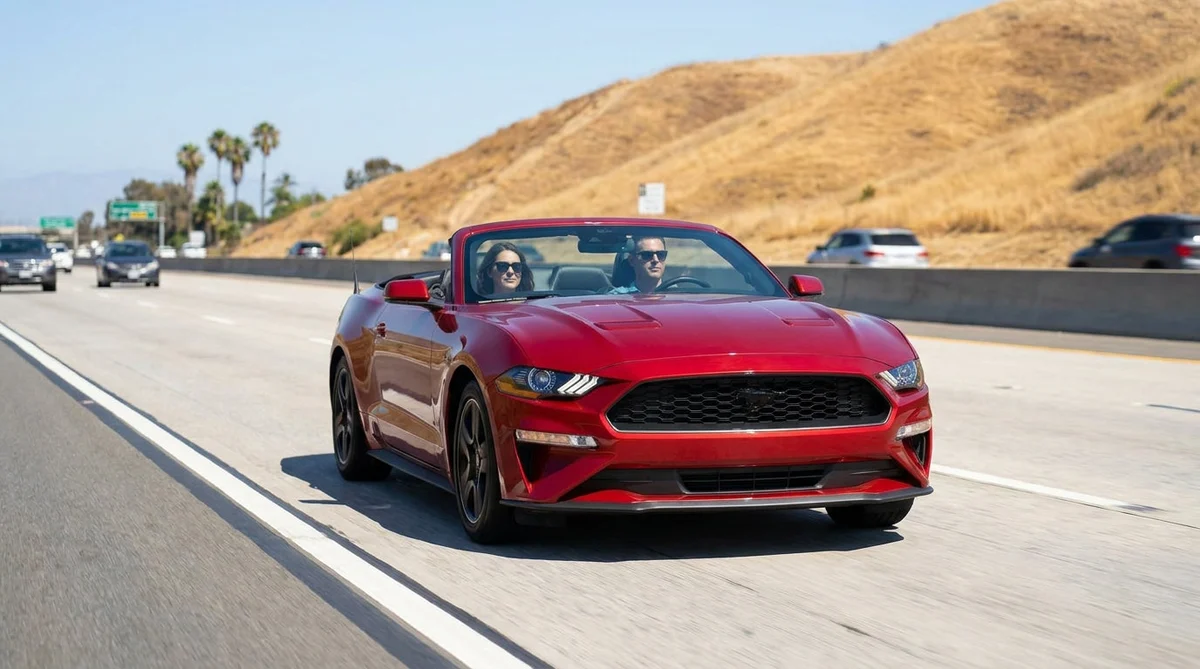 Silver car rental driving in a sunny California HOV lane marked with a white diamond painted on the asphalt