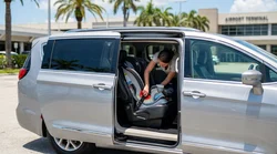 A child safety seat secured in the back seat of a car rental parked outdoors in sunny Florida