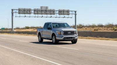 White car rental driving under a cashless toll gantry on a sunny Texas highway