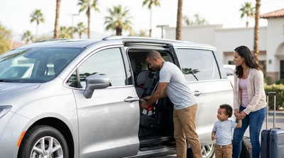 Child safety seat installed in the back of a car rental parked on a sunny street in California