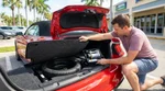 Open trunk of a white car rental parked on a sunny street in Florida showing a spare tyre