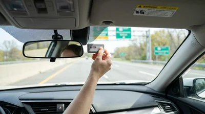 E-ZPass tag mounted on the windshield inside a car rental driving on a Pennsylvania highway