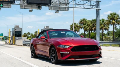 White car rental driving through an electronic toll plaza on a sunny Florida highway