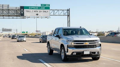 A family driving a car rental on a Texas highway passing an overhead HOV Express Lane sign