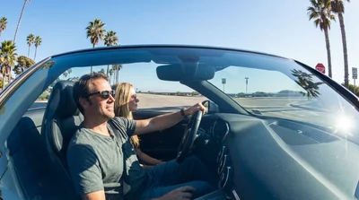 White car rental driving along a scenic coastal highway in California on a sunny day