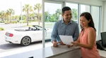Happy couple driving a car rental along a sunny coastal road in Florida
