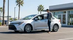 A white car rental driving along a sunny coastal highway overlooking the ocean in California