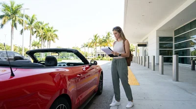 Person driving a white car rental along a scenic coastal highway in Florida