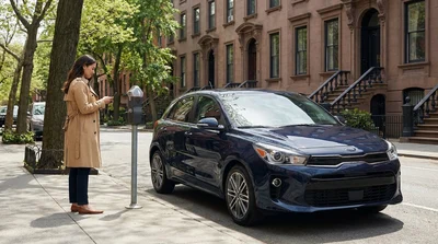Driver using a smartphone next to a parked car hire on a bustling New York street