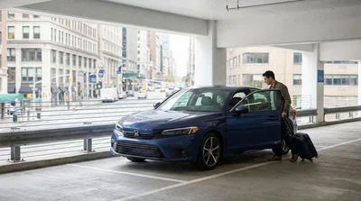 Driver navigating a modern car rental through a busy intersection in downtown New York