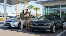 Customer looking at a row of parked vehicles at an outdoor car hire lot in Orlando